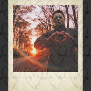 May include: A man wearing a white mask and a dark jacket makes a heart shape with his hands in front of a sunset background.