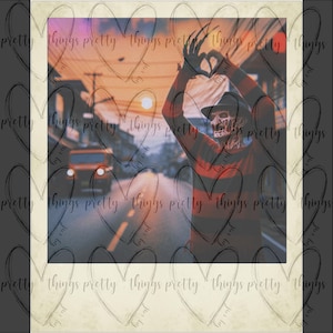 May include: A vintage-style photo of a person dressed as Freddy Krueger, the fictional horror character, standing in a street with a red and black striped sweater, a brown hat, and a glove with blades. The photo has a faded, vintage look and a heart-shaped frame.