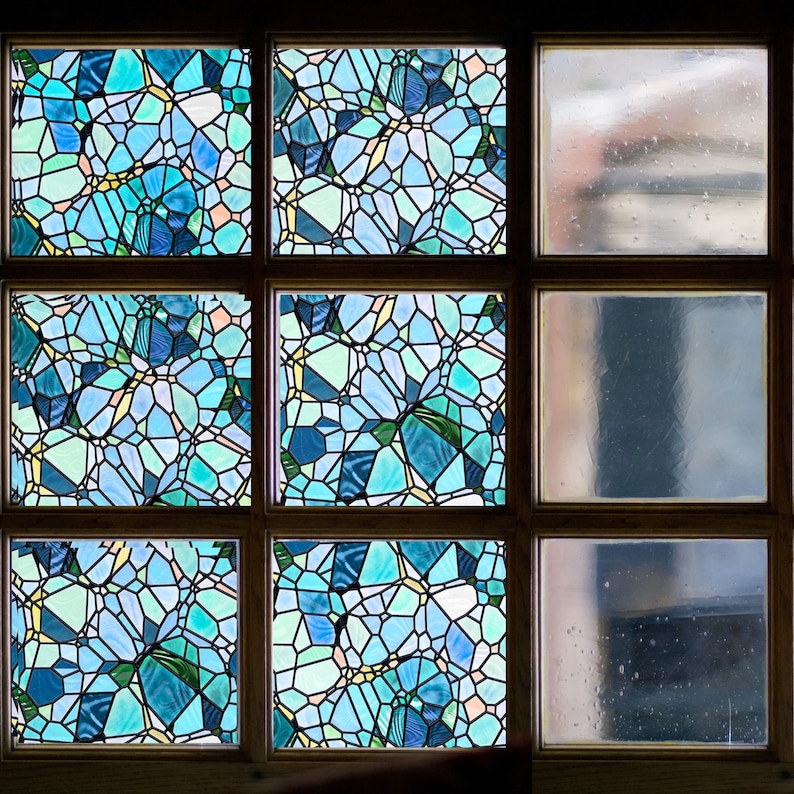 May include: A window with six panes of glass. The top three panes feature a blue and green stained glass design. The bottom three panes are clear glass.