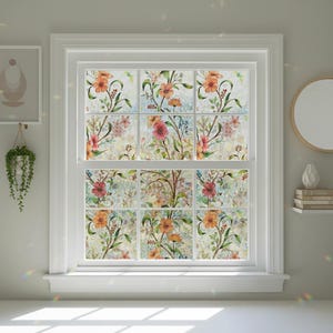 Peut inclure: Une fenêtre blanche ornée d'un motif floral. Le motif présente des fleurs orange, rouges et roses avec des tiges et des feuilles vertes. La fenêtre est divisée en neuf carreaux, chacun affichant une partie du motif floral. L'esthétique générale est douce et accueillante.