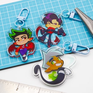May include: Three cartoon character keychains with blue clasps. One keychain features a character with green hair, red shirt, and purple pants. Another shows a character in a black and red outfit. The third keychain has a character with orange skin and white hair.