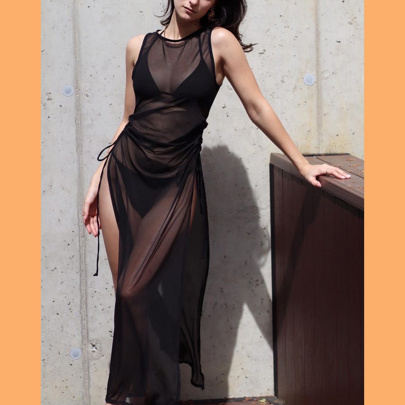 May include: A black sheer maxi dress with a side slit and a drawstring waist.