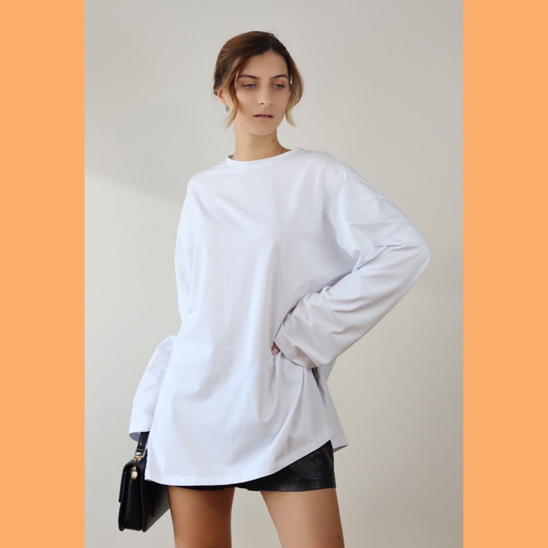May include: A white long-sleeved oversized t-shirt with a relaxed fit. The shirt is made of a soft, comfortable fabric and has a crew neckline.