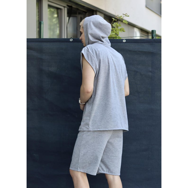 May include: A light gray sleeveless hoodie and matching shorts set. The hoodie has a hood and a relaxed fit. The shorts are knee-length and have a casual style. The outfit is made of a soft, comfortable fabric, perfect for lounging or casual wear.