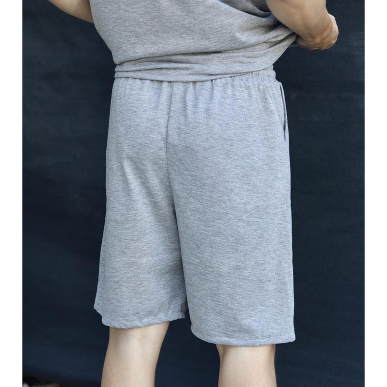 May include: Gray shorts with an elastic waistband. The shorts are made of a soft, knit fabric. The shorts are knee-length and have a relaxed fit. The shorts are part of a matching set with a gray t-shirt.