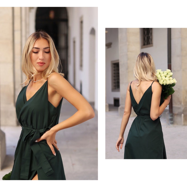 Puede incluir: Una mujer con un vestido verde oscuro de estilo envolvente con una tira fina. El vestido tiene un lazo en la cintura y una abertura en el lateral. La mujer est&aacute; de pie frente a un edificio.
