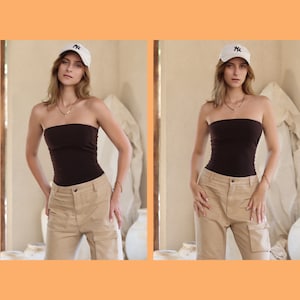May include: A woman wearing a brown strapless top and beige cargo pants. She is wearing a white baseball cap with a black logo.