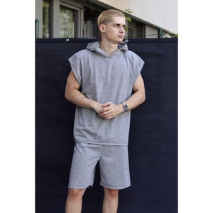 May include: A gray sleeveless hoodie and matching shorts set. The hoodie has a hood and a relaxed fit. The shorts are knee-length. The outfit is made of a soft, comfortable material, perfect for casual wear.