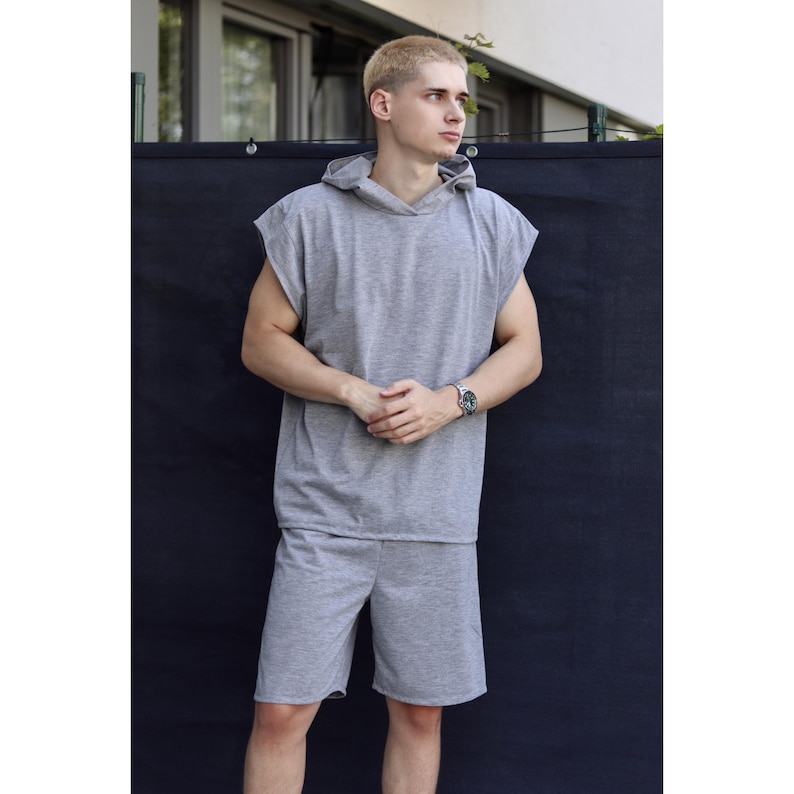 May include: A gray sleeveless hoodie and matching shorts set. The hoodie has a hood and a relaxed fit. The shorts are knee-length. The outfit is made of a soft, comfortable material, perfect for casual wear.