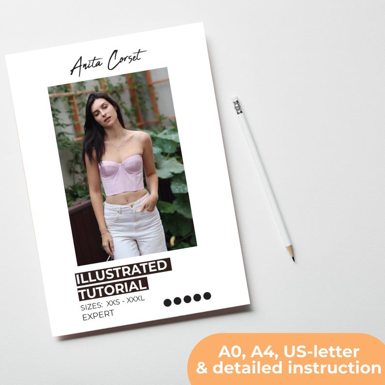 K&ouml;nnte beinhalten: Ein wei&szlig;es Papier mit dem Text "Anita Corset" und "ILLUSTRATED TUTORIAL" wird angezeigt. Das Tutorial umfasst die Gr&ouml;&szlig;en XXS-XXXL. Das Bild auf dem Papier zeigt eine Person, die ein rosa Korsett und eine wei&szlig;e Hose tr&auml;gt. Ein wei&szlig;er Bleistift befindet sich rechts.