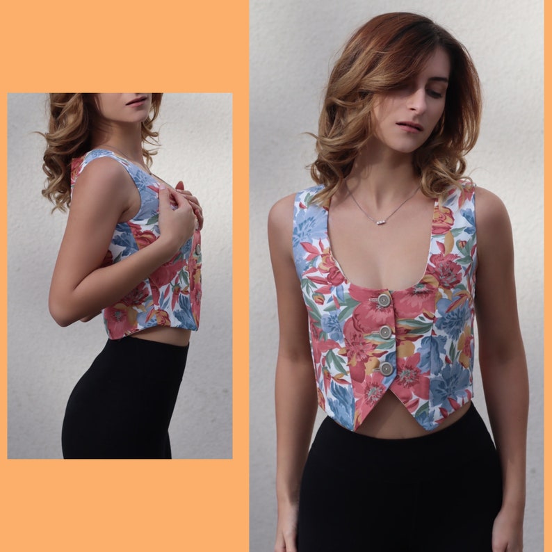 May include: A floral print vest with a button-up front and a scoop neck. The vest is white with pink, blue, and green flowers.