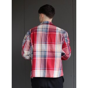 Pu&ograve; includere: Una camicia a quadri rossa, bianca e blu. La camicia ha maniche lunghe e un colletto. Il motivo a quadri &egrave; un design classico, adatto all'abbigliamento casual.