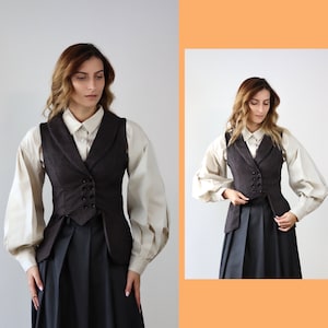 May include: A brown waistcoat with a white button-up shirt underneath. The waistcoat has a double-breasted closure and a pointed collar. The person is wearing a black skirt.