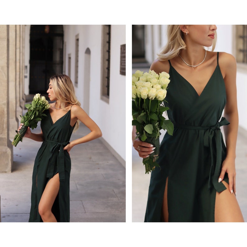 Puede incluir: Una mujer lleva un vestido maxi verde oscuro con escote en V y un lazo en la cintura. El vestido tiene una abertura en la pierna hasta el muslo a cada lado. Ella sostiene un ramo de rosas blancas.