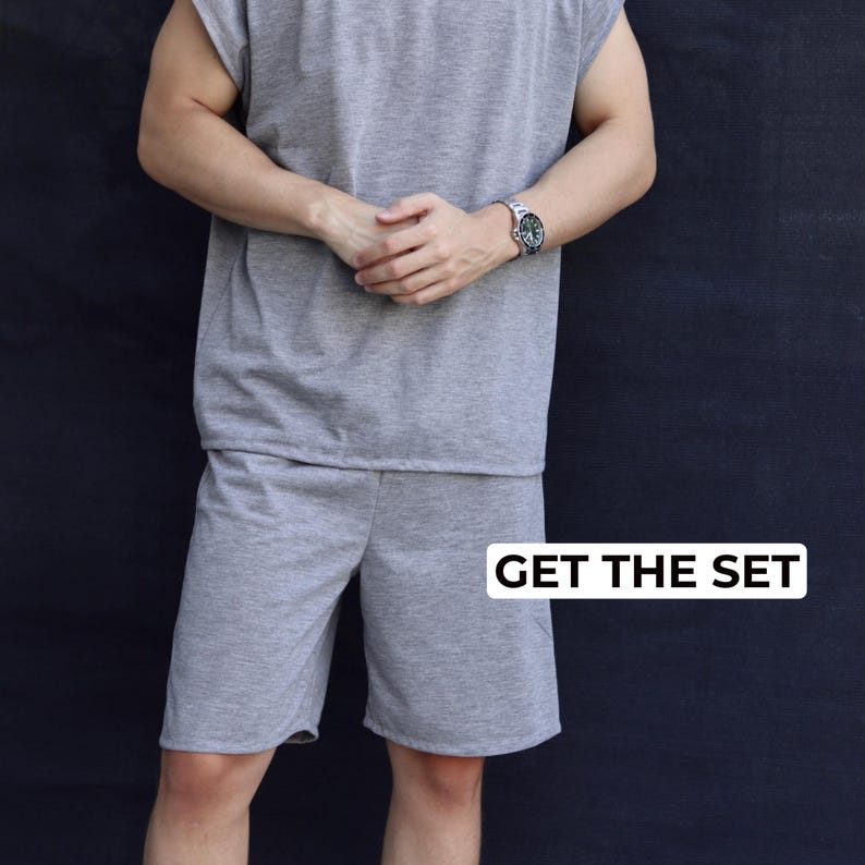 May include: A gray sleeveless shirt and matching shorts set. The outfit is made of a soft material and is displayed against a dark background. The text "GET THE SET" is in a white box.