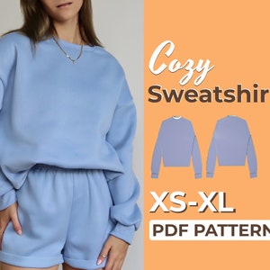 Peut inclure: Un sweat-shirt et un short assortis bleu clair avec le texte "Cozy Sweatshirt XS-XL PDF Pattern" sur un fond pêche.