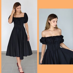May include: A black midi dress with a square neckline and puffed sleeves. The dress features a fitted bodice and a flared skirt, creating a classic silhouette. The dress is paired with red heels.