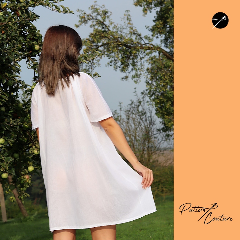 May include: A white, loose-fitting, short-sleeved dress with a round neckline. The dress is made of a lightweight fabric and has a flowing silhouette. The model is wearing the dress in a garden setting.