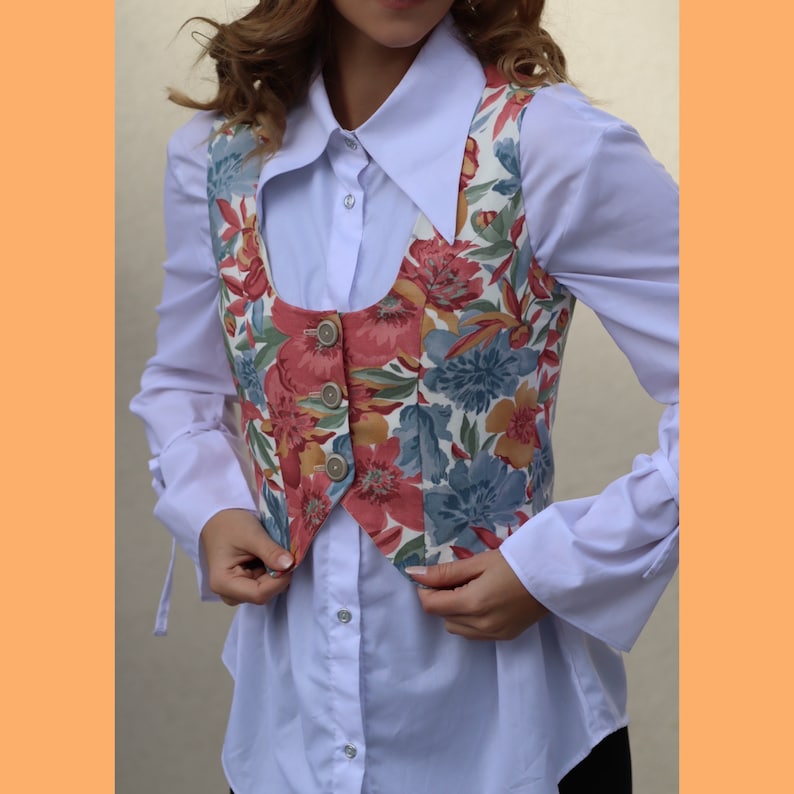 May include: A white button-down shirt with a floral print vest. The vest has a V-neck and buttons down the front.