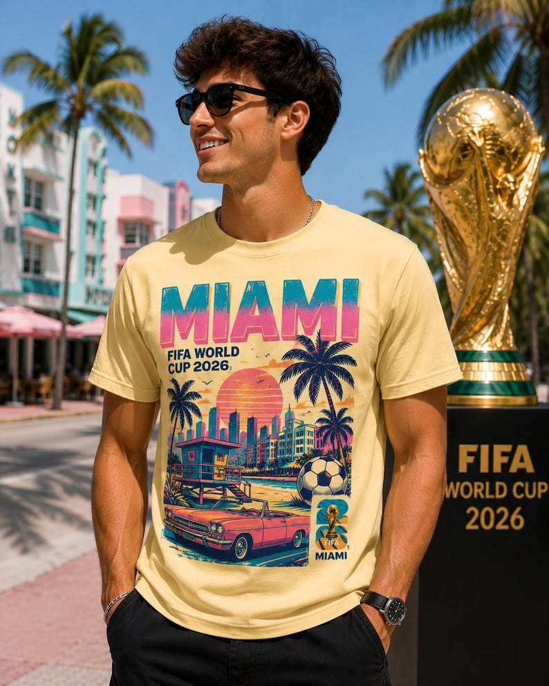 May include: A light yellow t-shirt with a graphic design featuring the word "MIAMI" in blue and pink, palm trees, a sunset, and a vintage car. The text "FIFA WORLD CUP 2026" is also displayed.
