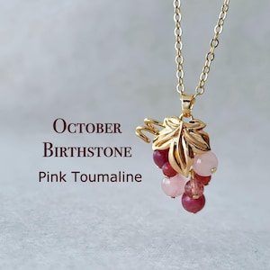 May include: October birthstone necklace with a gold leaf pendant and pink tourmaline beads. The pendant is shaped like a bunch of grapes.