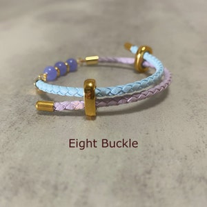 May include: A light blue and lavender braided leather bracelet with a gold buckle and lavender beads. The bracelet is called "Eight Buckle".
