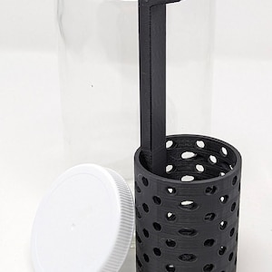 May include: A clear glass jar with a white lid and a black plastic insert with holes. The insert has a handle that attaches to the jar.