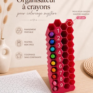 Peut inclure: Un organisateur de crayons en plastique rouge en forme de nid d'abeille avec des emplacements numérotés de 1 à 9. L'organisateur possède des compartiments hexagonaux d'un diamètre maximal de 1,5 cm, contenant des feutres insérés.