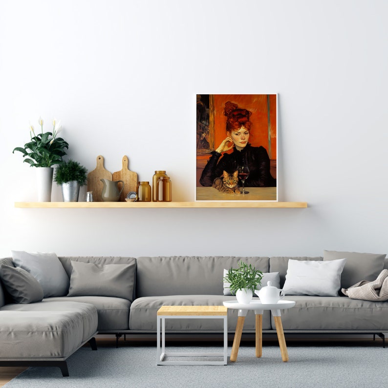 May include: A framed painting depicting a woman with red hair sitting with a cat. The woman is wearing a black dress and holding a glass of wine. The background is a warm orange colour.