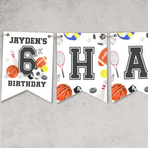 May include: White banner with a sports theme. The banner says "Jayden's 6th Birthday" and has images of basketballs, baseballs, volleyballs, bowling pins, tennis rackets, and soccer balls.