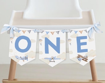 Könnte beinhalten: Ein blaues und weißes Banner mit dem Wort "ONE" in blauen Buchstaben. Das Banner ist mit kleinen Flugzeugen und Wolken verziert. Es ist perfekt für eine erste Geburtstagsfeier.