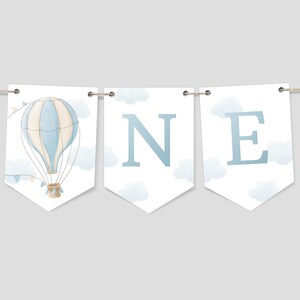 May include: A blue and white hot air balloon with a basket and clouds on a white banner with the word "ONE" in blue letters.