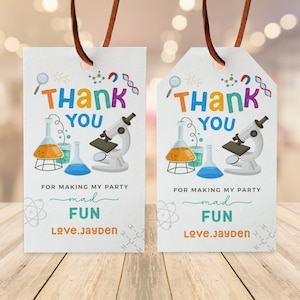May include: Two white thank you tags with colorful science themed illustrations. The text on the tags reads "Thank You" and "For making my party mad fun." The name "Love.Jayden" is printed on both tags.