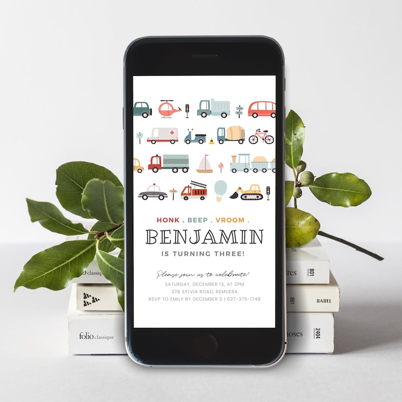 May include: A smartphone screen displaying a birthday invitation for a boy named Benjamin turning three. The invitation features a colorful illustration of various vehicles, including cars, trucks, helicopters, and a hot air balloon. The text on the invitation reads "HONK. BEEP. VROOM. BENJAMIN IS TURNING THREE! Please join us to celebrate! Saturday, December 13, at 2PM 378 Sylvia Road, Remuera RSVP to Emily by December 2 1 (027) 375-1748"