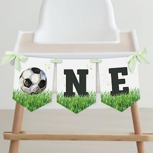 May include: A white and green banner with the word "ONE" in black letters. The banner has a soccer ball on the left side and green grass on the bottom.