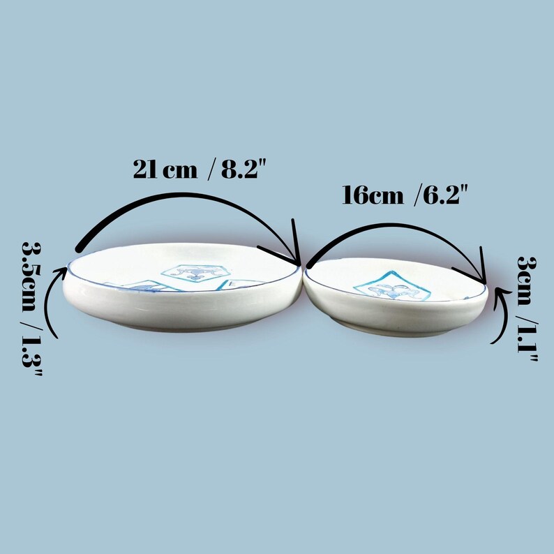 May include: Two white ceramic bowls with blue geometric designs. The larger bowl is 8.2 inches in diameter and 1.3 inches deep, while the smaller bowl is 6.2 inches in diameter and 1.1 inches deep. Both bowls have a blue rim.