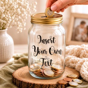 May include: A clear glass jar with a gold lid, filled with coins. The jar has the words "Insert Your Own Text" in black script. A hand is dropping a coin into the slot on the lid. The jar sits on a wooden slice.