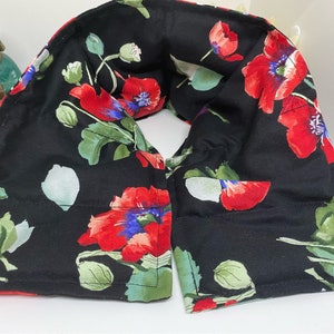 May include: Black neck wrap with a floral pattern featuring red poppies and green leaves. The wrap is made of fabric and has a sewn seam.