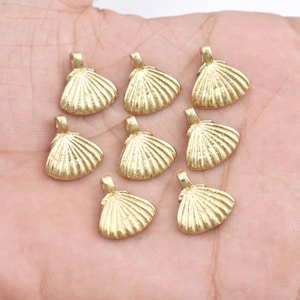 Puede incluir: Ocho abalorios de concha de mar de metal de color dorado con un bucle en la parte superior para sujetar a joyas u otras manualidades.