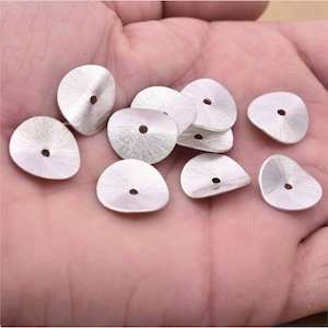 May include: A collection of silver-toned metal beads with a textured finish. Each bead has a small hole in the centre.