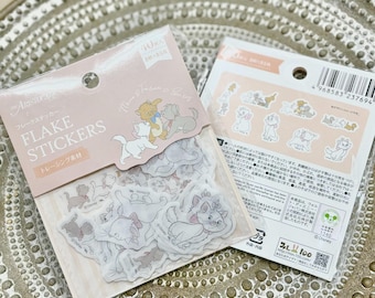 Puede incluir: Una hoja de pegatinas transparentes y translúcidas con varias imágenes de gatos de la película de Disney Los Aristogatos. Las pegatinas están sobre un fondo rosa y blanco con el texto "FLAKE STICKERS" y "トレーシング素材" en japonés.