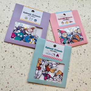 Puede incluir: Tres paquetes de escamas de sellado Upbeat Friends. Cada paquete tiene un fondo de color diferente y presenta una variedad de personajes de dibujos animados lindos. Los personajes incluyen una rana, un gato, un oso, un pingüino, un monstruo, un perro, un pájaro y una variedad de otros personajes.