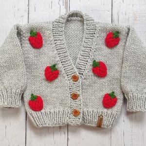 Personalized handknit strawberry cardigan with sleeve closed.