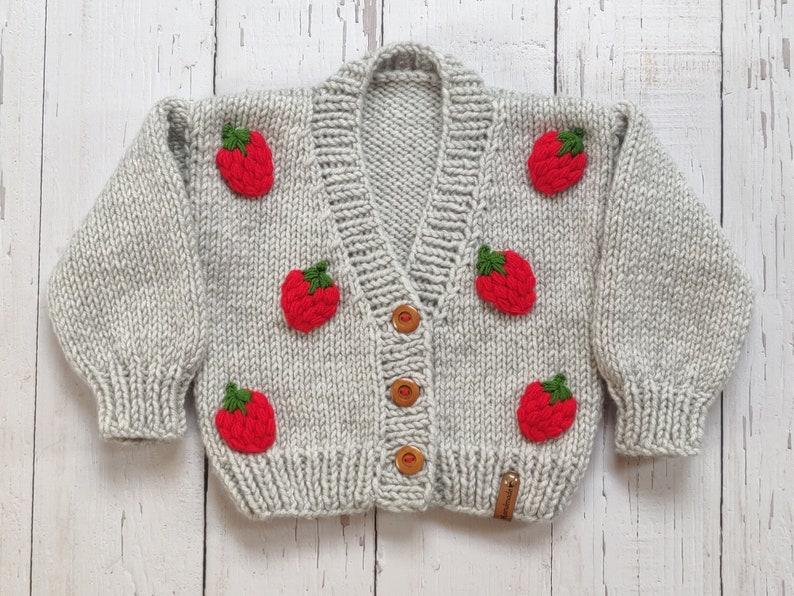 Personalized handknit strawberry cardigan with sleeve closed.