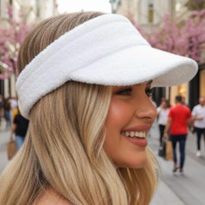 Puede incluir: Visera blanca de rizo con ala curvada. La visera está diseñada para proteger los ojos del sol. Este accesorio para la cabeza es popular para actividades al aire libre y deportes.