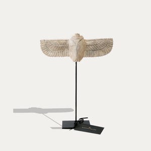 Può includere: Scultura di scarabeo in ceramica bianca con ali spiegate, montata su un supporto in metallo nero con un piccolo cartellino nero che recita "KING & PIN".