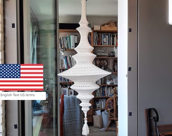 May include: A white, handcrafted, crochet pendant light fixture. The light has a tiered, elongated shape with a tassel at the bottom. The fixture is suspended from the ceiling, showcasing a unique, bohemian design.