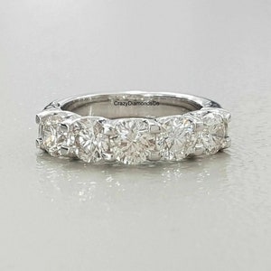 Puede incluir: Una banda de plata con una fila de cinco diamantes redondos engastados en canal. La banda es simple y elegante, y los diamantes brillan maravillosamente. El texto "CrazyDiamondsCo" está grabado en el interior de la banda.