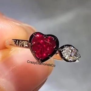 Ring met hartvormige rode robijn, zwarte rhodium rand en Toi Et Moi-zetting, 10 karaats geelgouden ring, mogelijkheid tot personalisatie met gravure.