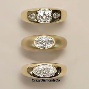 May include: Three gold rings with diamond center stones. The top ring has a cushion-cut diamond with two smaller side stones. The middle ring features an oval-cut diamond. The bottom ring has a marquise-cut diamond. The rings are displayed on a neutral background.
